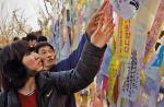Zwiedzający strefę zdemilitary-zowaną wieszają wstążki  z życzeniami zjednoczenia obu Korei