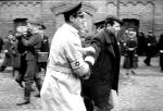 Niemiecki operator (na drugim planie, po lewej) filmuje tłum poganiany przez żydowską policję