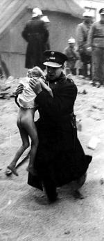 Rok 1932  – policjant  ratuje dziecko z zawalonego domu; miejsce nieustalone