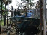 Żołnierze Sri Lanki oglądają łódź Tamilskich Tygrysów ukrytą wśród drzew