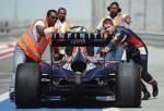 Mistrz świata Sebastian Vettel (pierwszy z prawej) pcha w Bahrajnie swój popsuty samochód do garażu