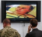Dziennikarz i żołnierz oglądają w Kijowie zeznania złapanego sierżanta Aleksandra Aleksandrowa