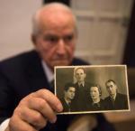 Leon Schwarzbaum, były więzień Auschwitz i świadek w procesie Reinholda Hanninga, prezentuje fotografię swoich rodziców i wuja zamordowanych w obozie