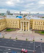 Potężna fasada gmachu KGB. Za nią znajduje się ponura Amerykanka 