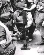 Grupa powstańców z kompanii „Janusza” Batalionu „Harnaś” oglądająca na podwórzu kamienicy przy ul. Świętokrzyskiej 20 brytyjski granatnik przeciwpancerny PIAT. Warszawa, 23 sierpnia 1944 r. 