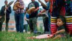 Eva William ze wspólnoty Simpcw First Nation gra na bębnie podczas demonstracji ku czci ofiar polityki asymilacyjnej przed budynkiem dawnej Kamloops Indian Residential School  w Kanadzie, 5 czerwca 2021 r.