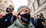 Demonstranci przed gmachem w maskach ze słynnym logo Memoriału 