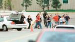 Students run from Columbine High School run under cover from police 20 April 1999 in Littleton, Colorado, after two masked teens on a 