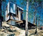 ZigZag Cabin w australijskim lesie. Kostka z zygzakowatymi oknami na stromym zboczu. Proj. Drew Heath, DREWheath.com 