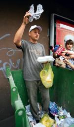 Dominik Dobrowolski nurkuje w pojemniku na śmieci w poszukiwaniu surowców wtórnych