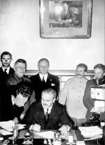 Wiaczesław Mołotow (podpisuje układ), za nim – Joachim  von Ribbentrop, obok – Józef Stalin, 23 sierpnia 1939 roku 