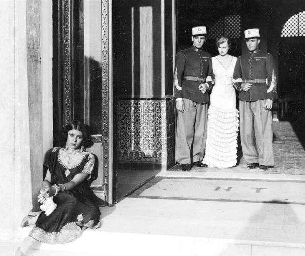 ≥Nora Ney jako Dżemila, żona szejka (siedzi przed wejściem), Adam Brodzisz jako sierżant Milczek (stoi z lewej), Maria Bogda jako Turystka (w środku) i Witold Conti jako Tarnowski w „Głosie pustyni” (1932 r.) 